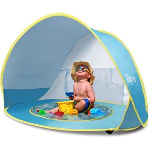 Baby sitzt in einer bunten Strandmuschel mit UV-Schutz, umgeben von Spielzeug, ideal für sonnige Tage am Strand oder Freibad.
