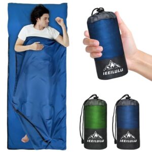 Schlafender Mann in einem blauen Hüttenschlafsack aus Baumwolle mit zwei-Wege-Reißverschluss, umgeben von kompakten Schlafsäcken für Camping und Reisen.