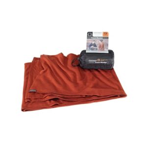 Luxuriöse COCOON Reisedecke aus Merinowolle und Seide in Dark Terracotta, ideal für Reisen und gemütliche Abende.