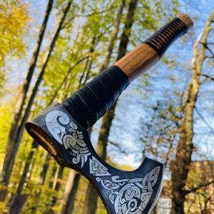 Crafttal Wikinger Axt aus Kohlenstoffstahl mit Eschenholzgriff, rustikal und handgefertigt, vor herbstlicher Landschaft fotografiert