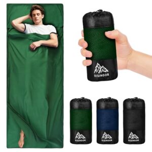 Hüttenschlafsack aus Baumwolle in grün, ideal für Camping und Reisen, mit einer Person, die entspannt darin liegt, und einem zusammengerollten, kompakten Schlafsack daneben.