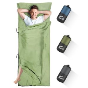 junger Mann im Hüttenschlafsack aus Mikrofaser, liegend und entspannt, umgeben von mehreren kompakten Schlafsackmodellen in verschiedenen Farben, ideal für Outdoor-Abenteuer und Reisen.
