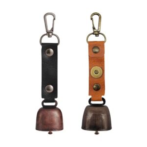 Zwei Vintage Kupferglocken mit Lederbefestigungen, ideal für Haustiere und Outdoor-Aktivitäten. Die linke Glocke hat eine rauhe kupferartige Oberfläche, die rechte Glocke ist dunkler und matter, beide mit praktischen Clips zum Befestigen.