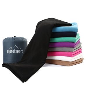 Mikrofaser Fleece Decke mit Schlafsackfunktion in schwarz, ideal für Camping und Outdoor-Aktivitäten, auf einem Stapel mit verschiedenen farbigen Textilien.