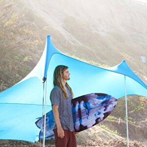 Neso Grande Beach Zelt in einer idyllischen Strandumgebung mit einem Mann, der bereit ist, den Sonnenschirm und das Surfboard in der Nähe zu genießen. Das Zelt bietet Schutz vor Sonnenstrahlen und eine gemütliche Atmosphäre für entspannte Tage am Strand.
