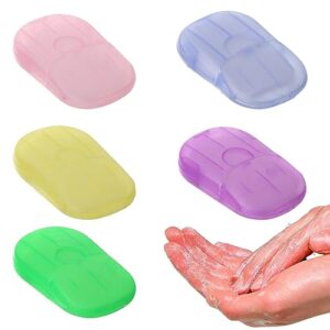 Papierseifenblätter in verschiedenen Farben, die in einer praktischen Verpackung angeordnet sind, zusammen mit einer menschlichen Hand, die die Seife benutzt, ideal für Reisen und Outdoor-Aktivitäten.