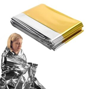 Person in silberner Rettungsdecke, die Licht und Wärme reflektiert, mit goldener Seite oben, umgeben von weiteren Rettungsdecken, ideal für Outdoor-Aktivitäten und Notfälle