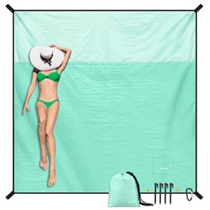 Entspannte Person auf einer großen, sanddichten Stranddecke in Mintgrün, ideal für den Strand oder Picknick, mit grünem Bikini und Sonnenhut.