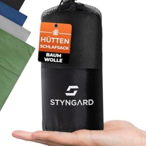 STYNGARD 2in1 Hüttenschlafsack aus 100% Baumwolle in einer schwarzen Transporttasche, ideal für Reisen und Camping. Kompakt und leicht, zeigt die praktische Handhabung.