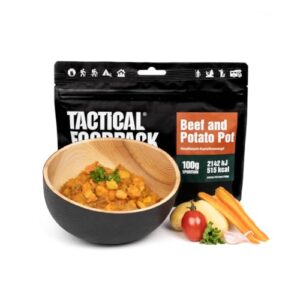 Tactical Foodpack mit Beef and Potato Pot in einer dekorativen Holzschüssel, umgeben von frischen Zutaten wie Tomaten, Kartoffeln und Kräutern.