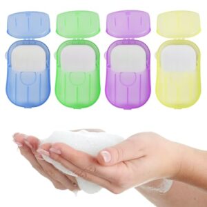 Vier kleine, bunte Behälter mit aufklappbaren Deckeln, gefüllt mit Mini-Seifenblättern, ideal für die persönliche Hygiene unterwegs.