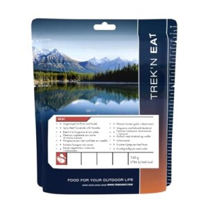 TREK'N EAT Ungarntopf mit Rindfleisch und Nudeln in umweltfreundlicher Verpackung für Outdoor-Aktivitäten, umgeben von einer beeindruckenden Berglandschaft.