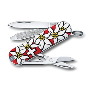 Victorinox Schweizer Taschenmesser Classic SD in Edelweiss-Design mit 7 Funktionen. Klinge, Nagelfeile und Schere ausgeklappt, florales Muster mit Edelweiss-Blüten.