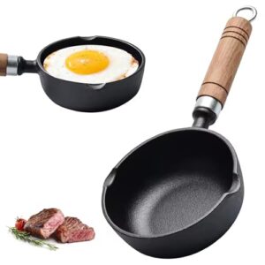 Kleine gusseiserne Pfanne mit Holzgriff, gefüllt mit einem perfekt gebratenen Spiegelei und gegrilltem Fleisch, umgeben von frischen Kräutern.