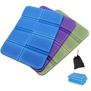 Drei faltbare, wasserfeste Sitzkissen in Blau, Lila und Olivgrün, ideal für Outdoor-Aktivitäten wie Camping und Wandern, neben einem praktischen Aufbewahrungstäschchen.