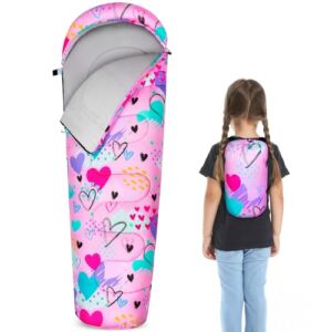 Kind in einem pinken Schlafsack mit Herzsymbolen am Campingplatz