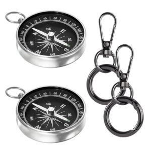 Zwei wasserdichte Kompass-Anhänger mit silberner und schwarzer Farbe, jeweils mit Gold-Rahmen und Hand-Design. Sie sind an einem silbernen Kettchen befestigt. Ideal für Outdoor-Aktivitäten wie Wandern und Camping.